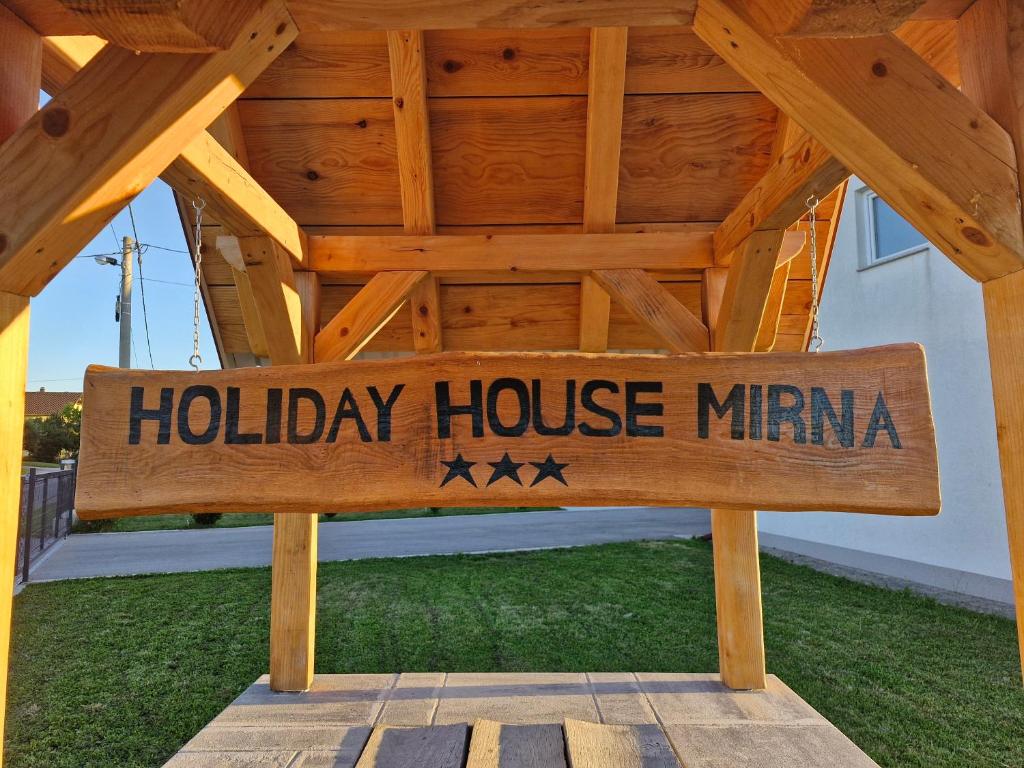 un cartello di legno con la scritta "casa vacanze minima" sotto un tetto di Kuća za odmor Mirna a Gospić