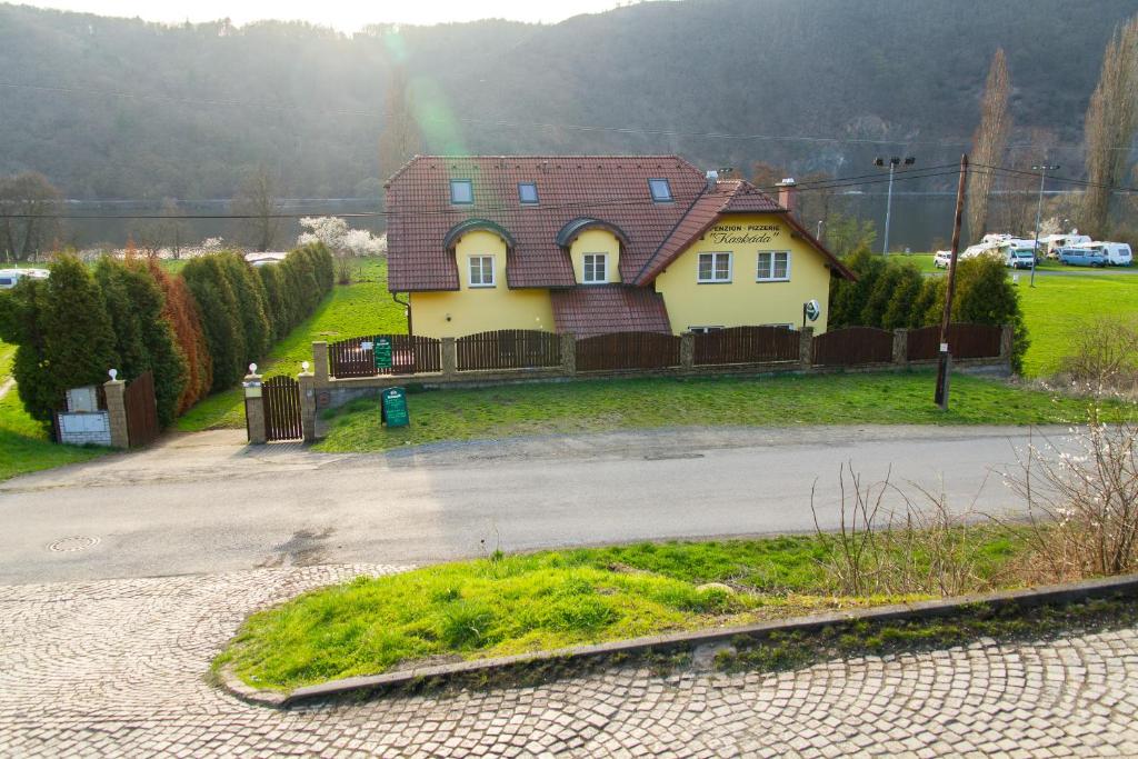 a yellow house with a red roof and a rainbow at Guest House Kaskáda in Vrané nad Vltavou
