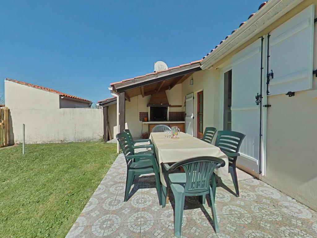 un patio avec une table et des chaises sur l'herbe dans l'établissement Maison plain pied tout confort, proche plage, 6 couchages, terrasse, 2 chambres, parking, Wi-Fi optionnel - FR-1-224A-383, à Bretignolles-sur-Mer