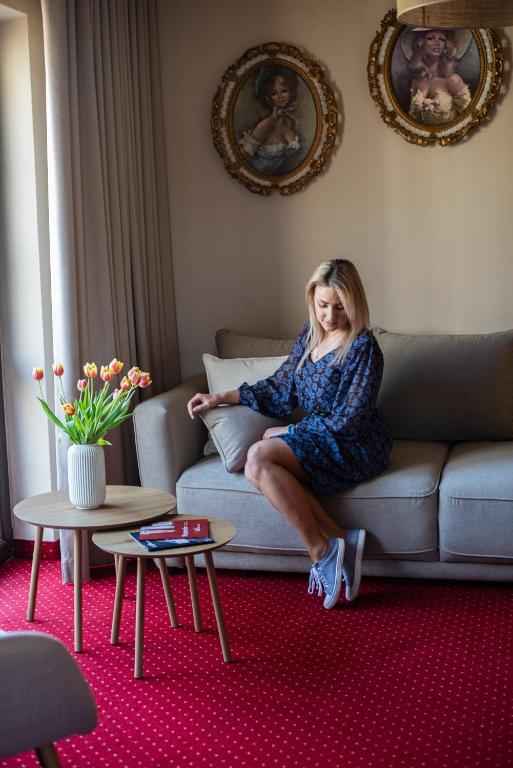a woman sitting on a couch in a living room at Hotel Restauracja Jaś Wędrowniczek in Rymanów