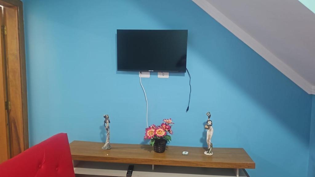une pièce avec une table avec une télévision sur un mur bleu dans l'établissement Casa na Praia Grande, à Praia Grande