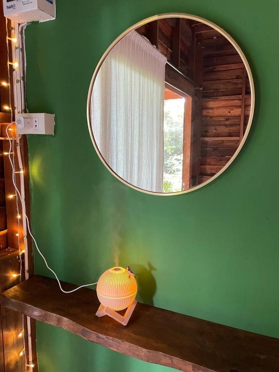 a mirror on a green wall with a vase on a shelf at Unity coliving in Thong Sala