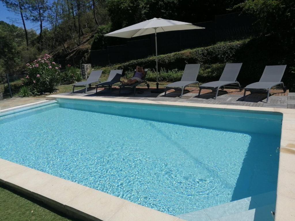 une femme assise sur des chaises à côté d'une piscine dans l'établissement Maison avec piscine dans les Cévennes, à Saint-Paul-la-Coste