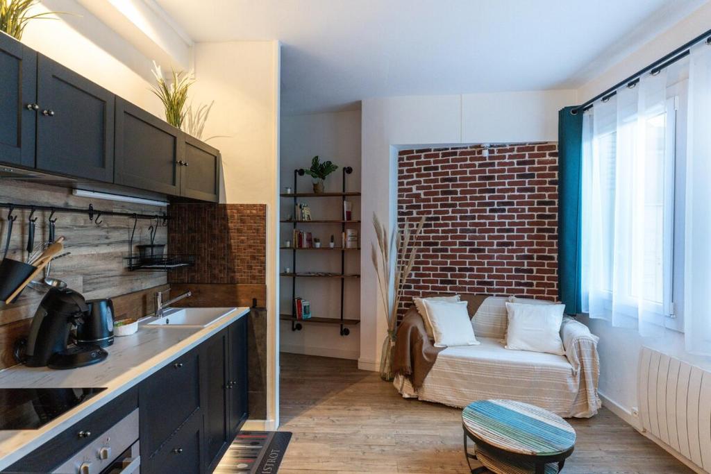 une cuisine avec un canapé en face d'un mur de briques dans l'établissement L'atelier caché, à Toulouse