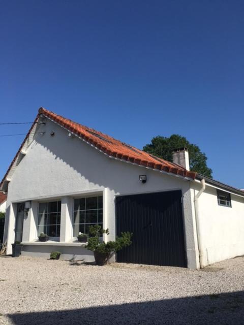 un bâtiment blanc avec garage et porte dans l'établissement Villa des 4 saisons, à Cucq