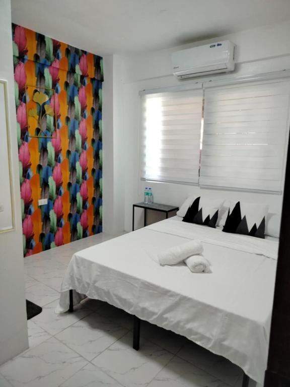 a bedroom with a large white bed with black pillows at Marias couple room in Puerto Galera
