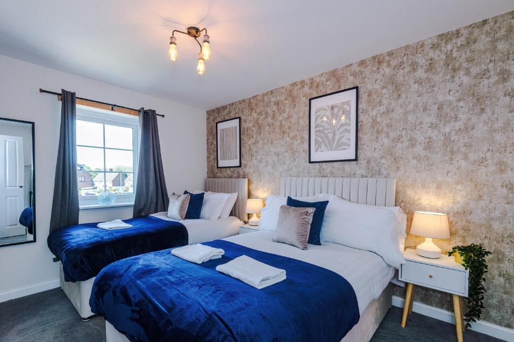 two beds in a bedroom with blue and white at 3 Bedrooms Driveway Walk 2 JLR Halewood Airport - 5 Beds- 3 WC-Speke Boulevard-South Liverpool-Sleeps 9 - Fully Equipped- Docks- Waterfront Bank Arena Liverpool by Arz Stays in Liverpool