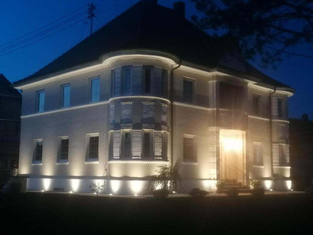 a large white building with its lights on at Villa Romantika in Ichenhausen