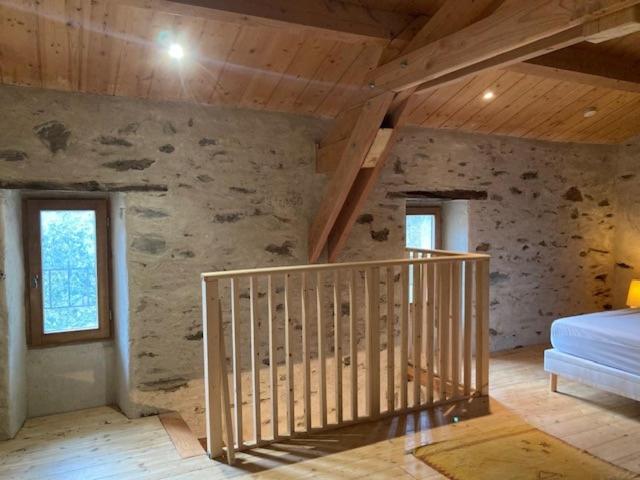 Habitación con escalera y pared de piedra. en Gîte Le COCON au Clarou, en Valleraugue