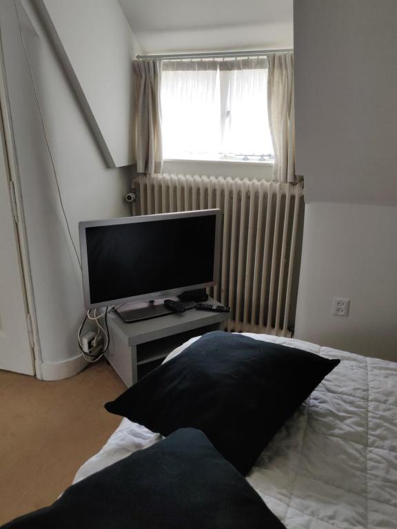 a bedroom with a tv and a bed with a pillow at Zit slaapkamer op de 2e etage in een rietgedekte villa met gedeelde douche en keuken in Wassenaar