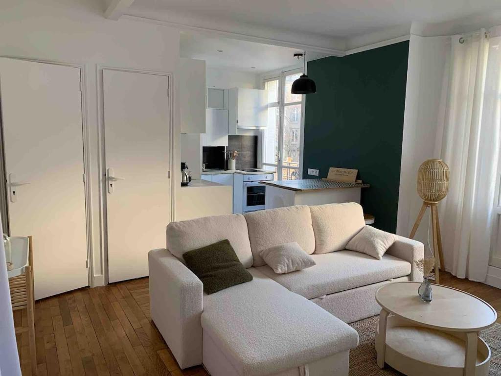 un salon avec un canapé blanc et une cuisine dans l'établissement Cosy 2 pièces 1 Chambre , 1 séjour, et 1 coin bureau, à Boulogne-Billancourt