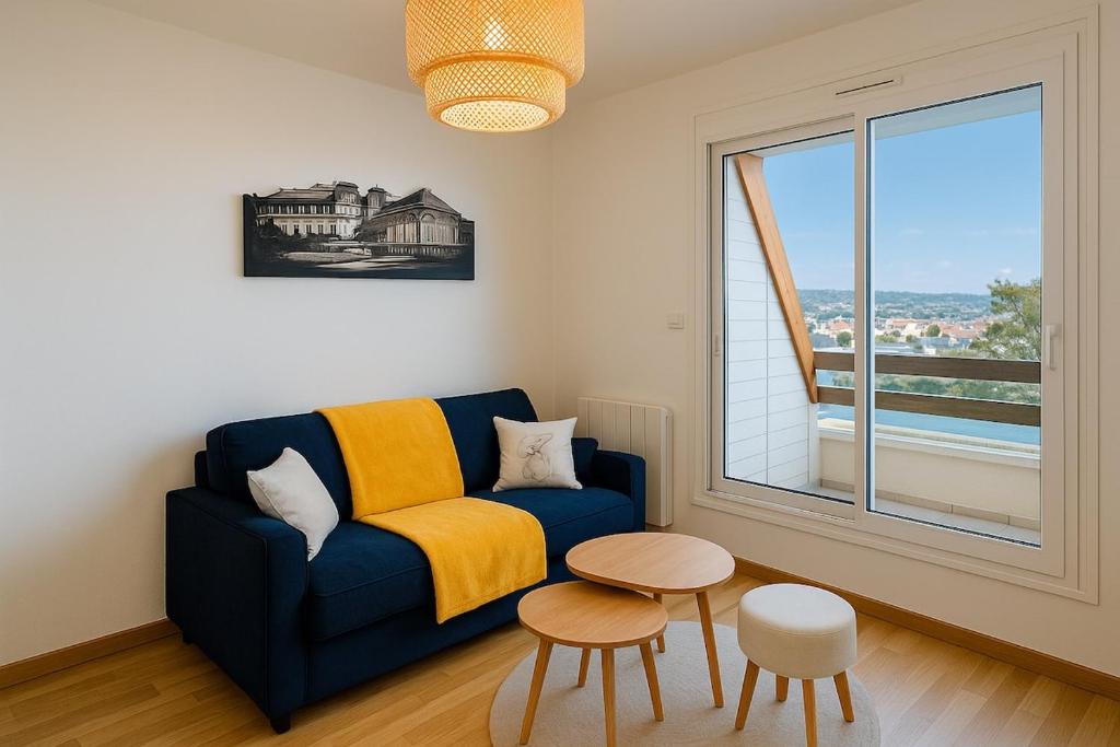 un salon avec un canapé bleu et une fenêtre dans l'établissement Charmant 2 pièces à Cabourg - 80 m de la plage, à Cabourg