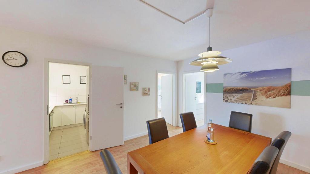 a dining room with a table and chairs and a clock at Berner Bude 5, 3SZ, 6P, TV, Wlan in Hamburg
