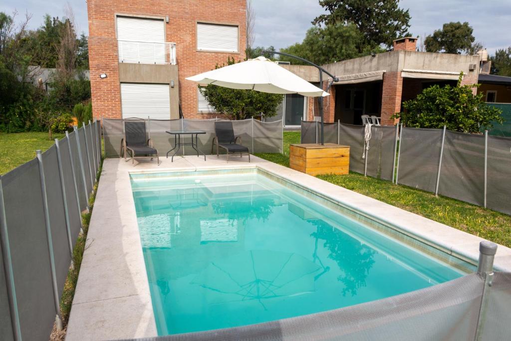 einen Pool mit einem Tisch und einem Sonnenschirm in der Unterkunft Casa El Descanso in Paraná