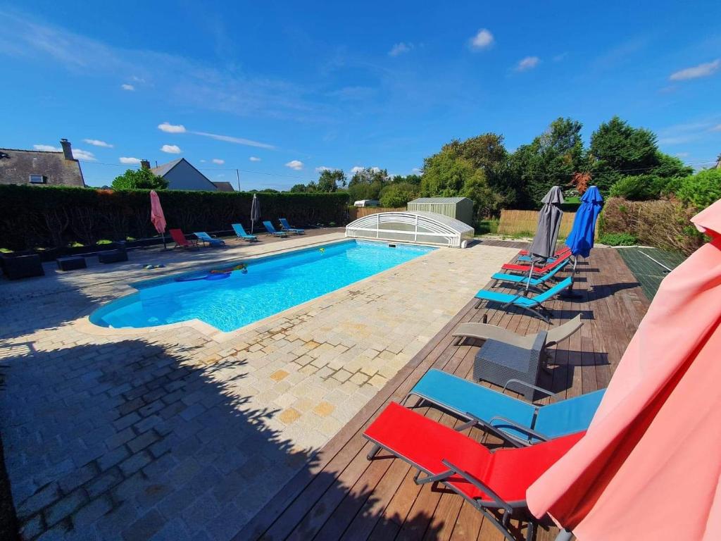 une piscine avec des chaises et des parasols à côté dans l'établissement Les Moineaux, à Val Couesnon