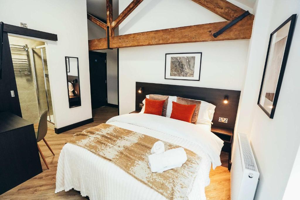 ダービーにあるNo46 Stylish City Studio Apartment, By DerBnBのオレンジ色の枕が付いた大きな白いベッドのある寝室