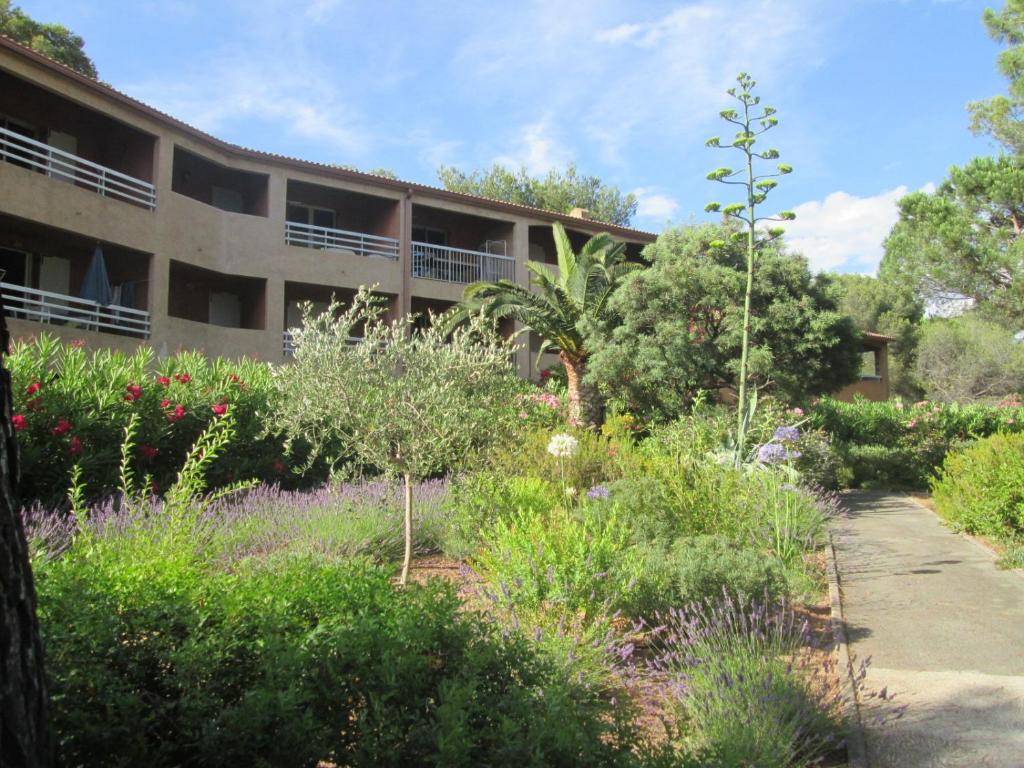 un jardin en face d'un bâtiment fleuri dans l'établissement Résidence Pinede Mer Soleil, à Saint-Raphaël