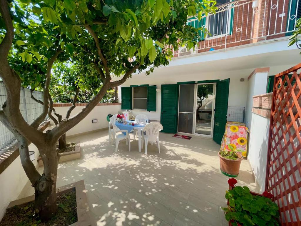 un patio con tavolo e sedie sotto un albero di Scalingi Family Apartments a Sperlonga