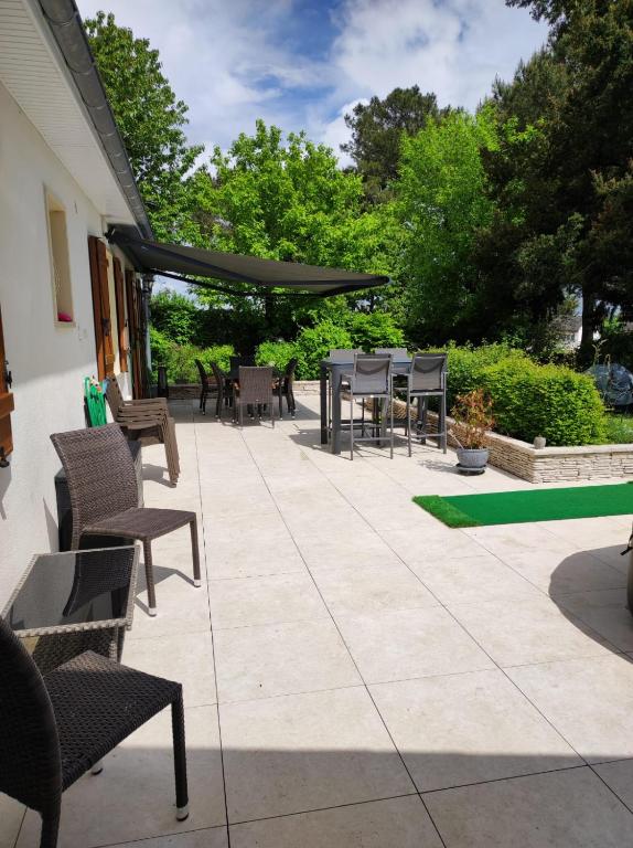 d'une terrasse avec des chaises, une table et des chaises. dans l'établissement Maison Du cerf - proche du circuit et du golf des 24H, à Mulsanne