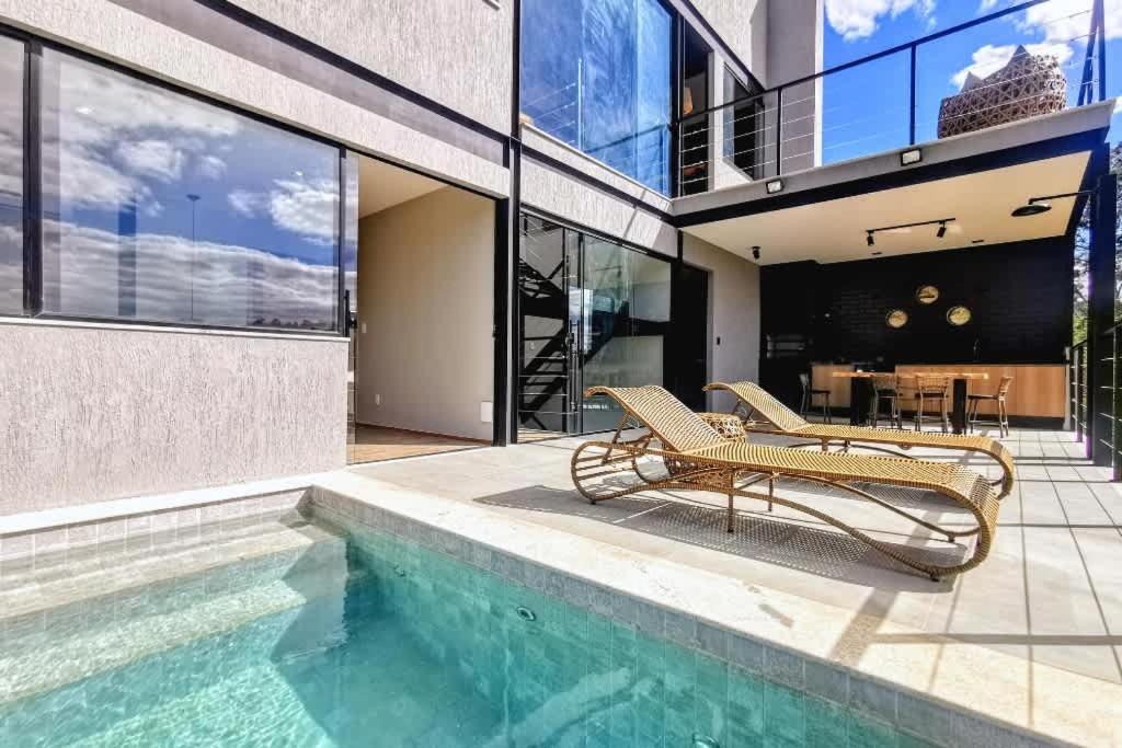 ein Haus mit einem Pool und zwei Stühlen daneben in der Unterkunft Lux 28 - Casa moderna piscina aquecida e vista in Teresópolis