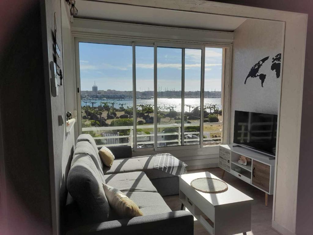 un salon avec un canapé et une grande fenêtre dans l'établissement Bellevue au cap d agde, au Cap d'Agde