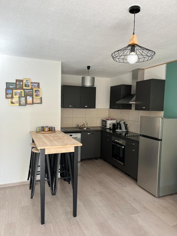 une cuisine avec des appareils en noir et blanc et une table dans l'établissement Le Lorain cozy avec terrasse, à Épinal