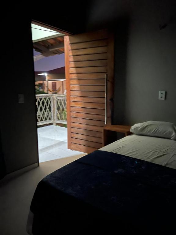 ein Schlafzimmer mit einer Tür zum Balkon in der Unterkunft Chalé Casa Moitas in Amontada