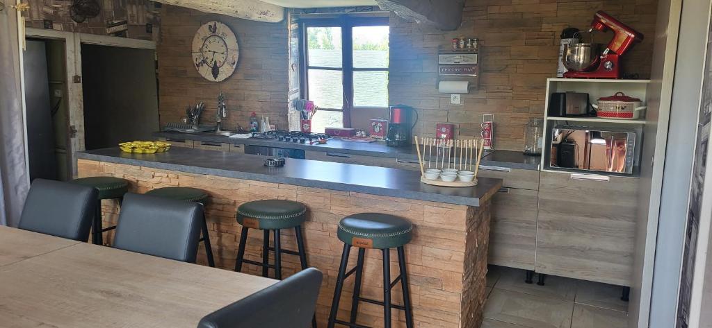 une cuisine avec un comptoir et des tabourets dans une pièce dans l'établissement la maison du hobbit, à Flamets-Frétils