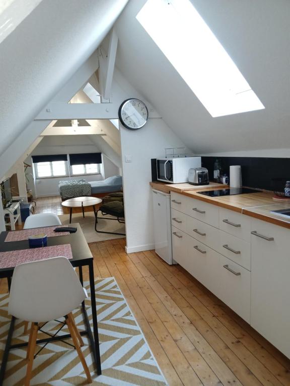 a kitchen with white cabinets and a clock on the wall at Le Coucou Rennais in Rennes