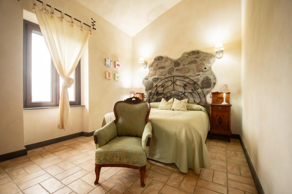 a bedroom with a large bed and a chair at Agriturismo Re Tarquinio in Tuscania