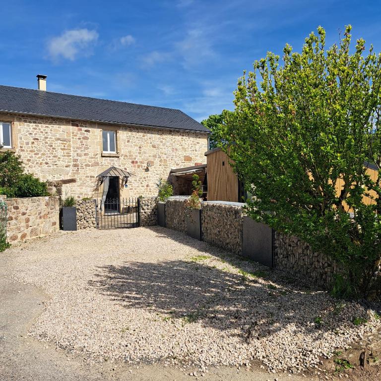 une maison en briques avec une clôture devant elle dans l'établissement Le Crochet de Pervenche, à Recoules-Prévinquières