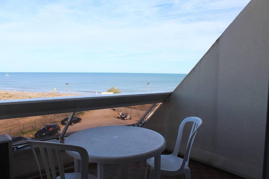 une table et des chaises sur un balcon avec vue sur la plage dans l'établissement Studio Héliopolis AB 310 - 3 personnes, au Cap d'Agde