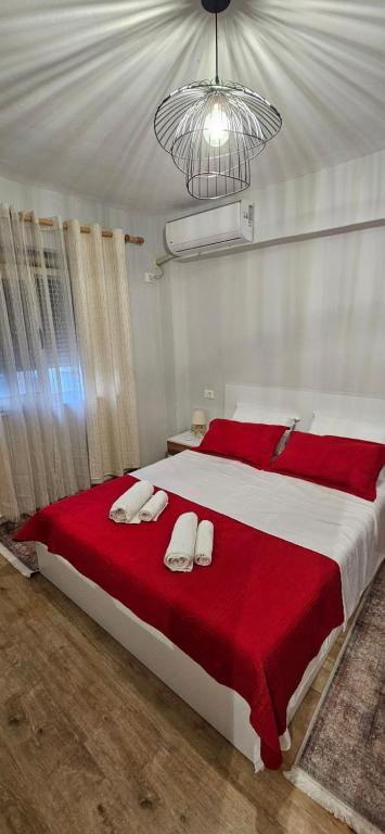a bedroom with a large bed with red and white sheets at Library Apartment by Bohem Rentals in Durrës