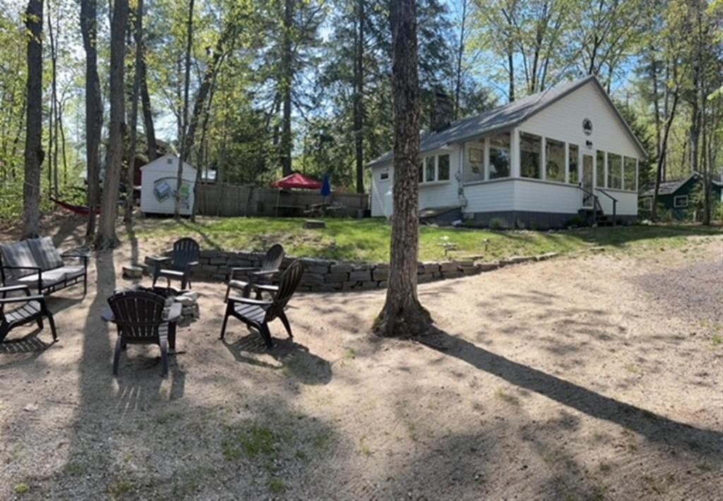 a house with a group of chairs and a tree at KENDALL COTTAGE LIMIT 6 villa in North Sebago
