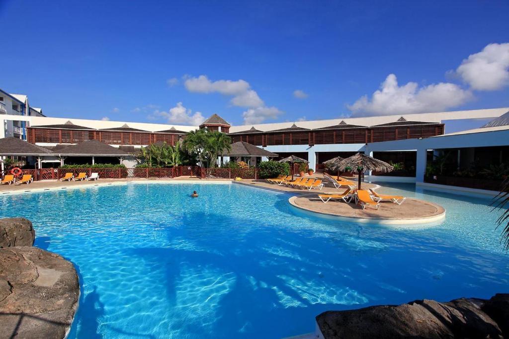 a large swimming pool with chairs and an umbrella at Ti Boubou Gwada Saint François, Vue Mer, Cuve à Eau, Parking Privé in Saint-François