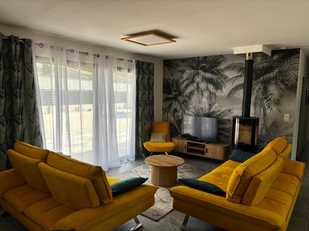 un salon avec deux canapés jaunes et une télévision dans l'établissement Gîte de Montfort, à Caromb