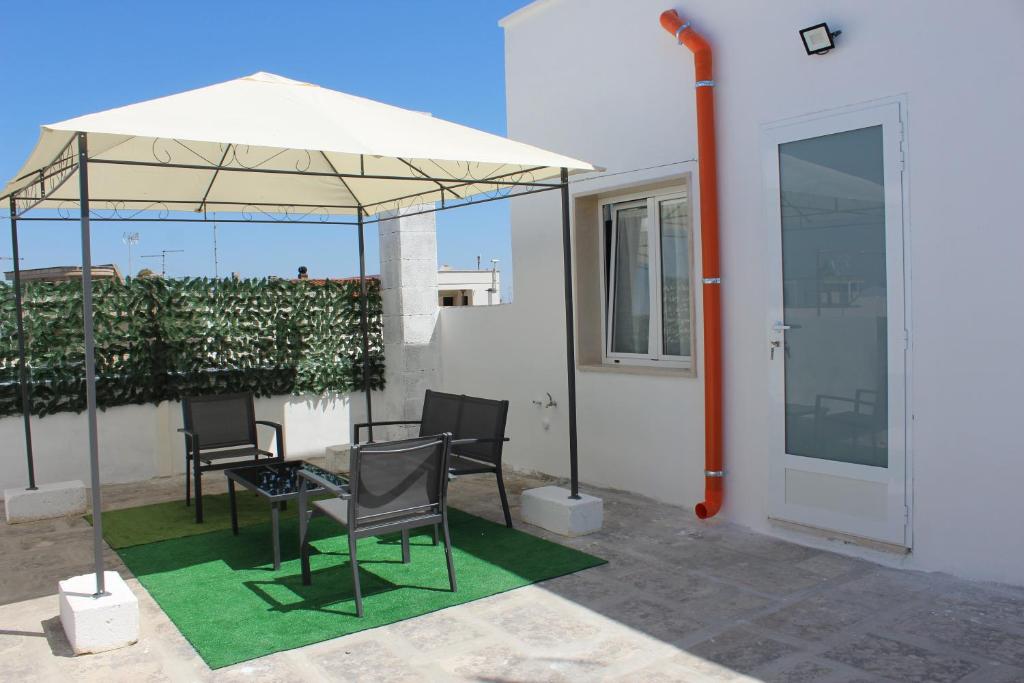 een patio met een tafel en stoelen onder een parasol bij D&C House in Galatone