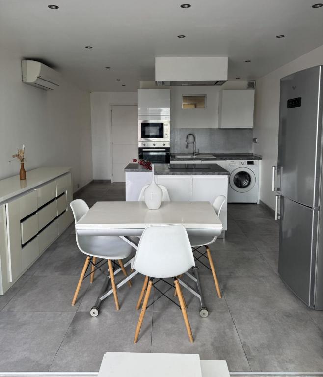 - une cuisine avec une table blanche et des chaises blanches dans l'établissement Petit Nid Pieds dans l'eau, à Sausset-les-Pins