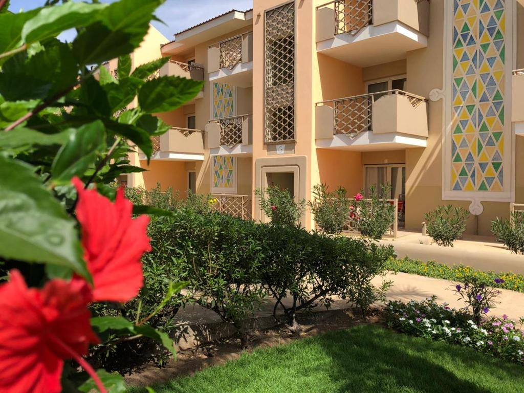 an apartment building with a courtyard with red flowers at Tropical Casa Castanha in Santa Maria