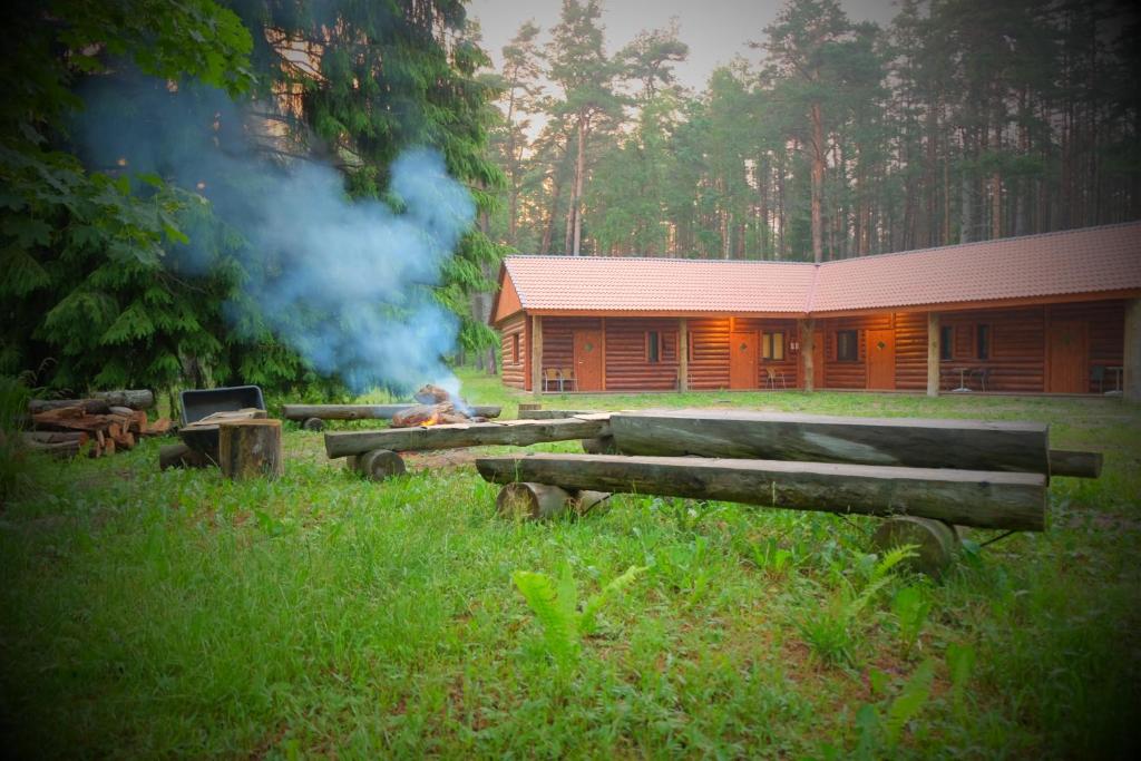 uma cabana de madeira com uma lareira em frente em Kallaste Talu- Turismitalu & Holiday Resort em Padise