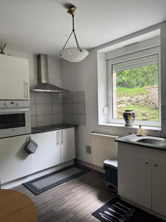 a kitchen with white cabinets and a sink and a window at 200 m centre ville maison mitoyenne avec place de parking gratuite in Épinal