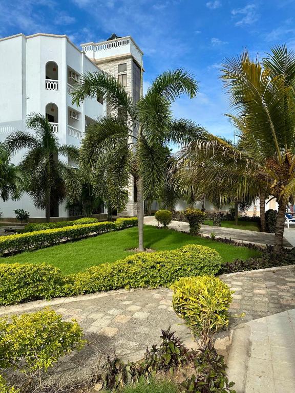 a white building with palm trees in front of it at Clalem Condos Diani Beach in Diani Beach