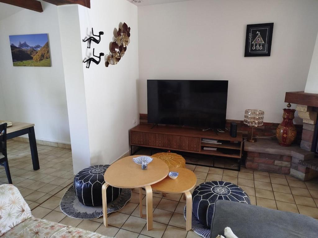 un salon avec une télévision et une table dans l'établissement Maison le Cerisier, à Amiens