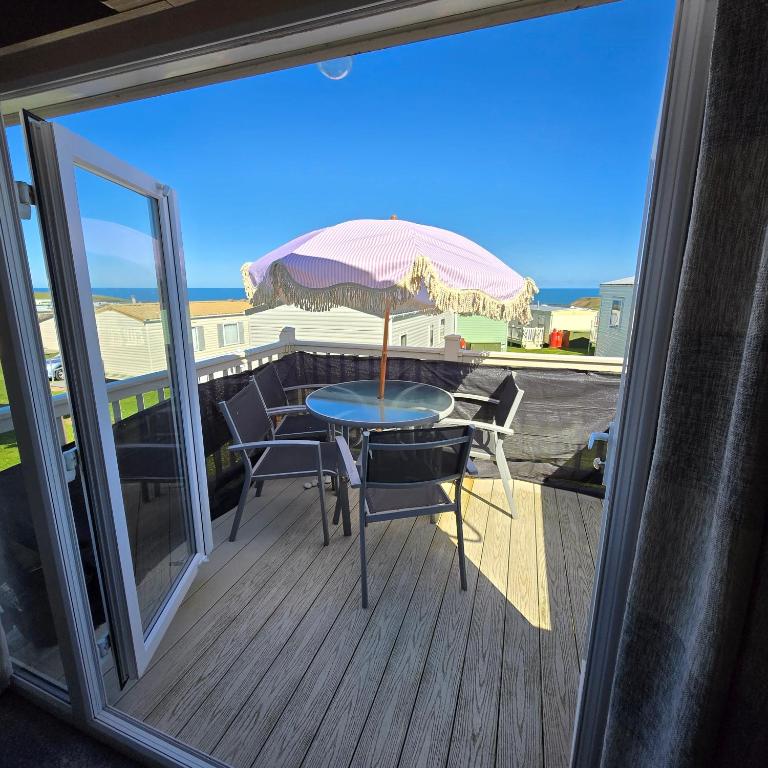 a table and chairs on a deck with an umbrella at Thornwick bay Yellowhammer 28 in Flamborough