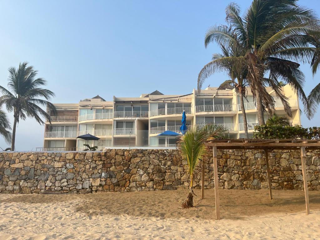 a hotel on the beach with palm trees and a wall at 106 THE BEST SUNSeT in Coyuca de Benítez