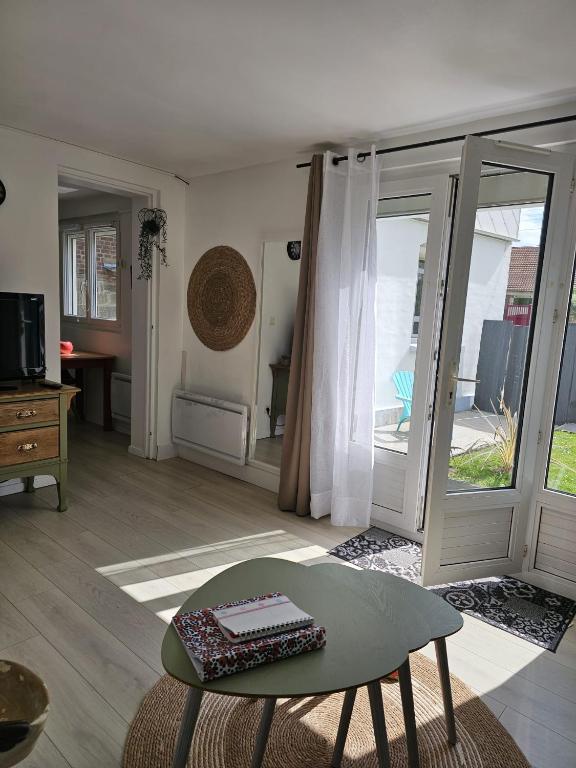 d'un salon avec une table et une porte coulissante en verre. dans l'établissement Nid de verdure à 15 minutes centre et plage, au Havre