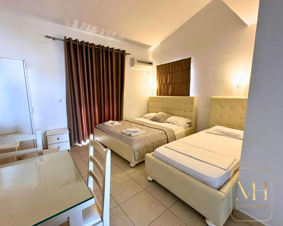 a hotel room with two beds and a desk at Hotel Marku in Ksamil