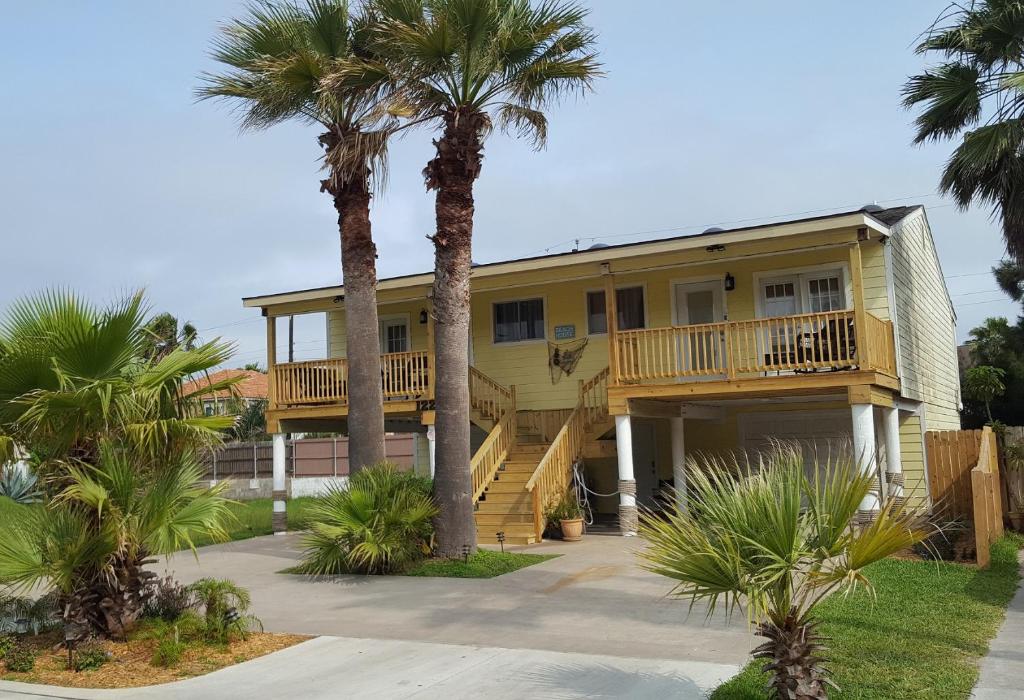a yellow house with palm trees in front of it at The Kingfish Cottage in South Padre Island