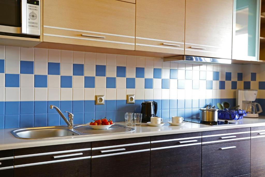 a kitchen with a sink and blue and white tiles at Sirena Residence & Spa in Marathokampos