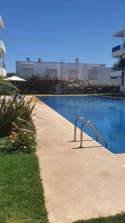a swimming pool with a hand rail next to a building at Ground floor apartment - Residence Skhirat Beach 2 in Skhirat